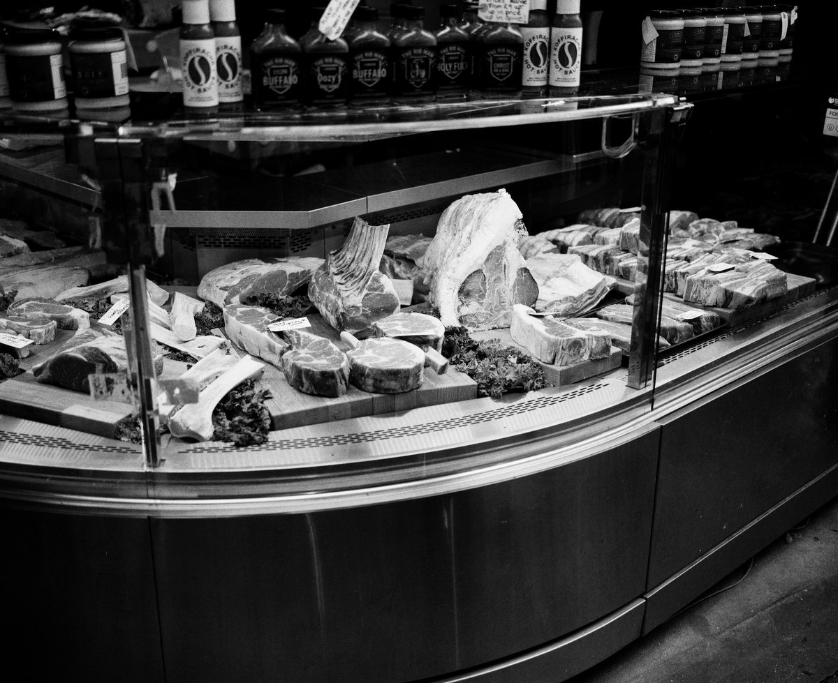 A butcher's counter in black and white, cuts of meat laid out behind curved glass